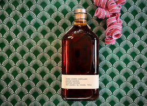 Bottle image of Peated Bourbon on festive holiday background.